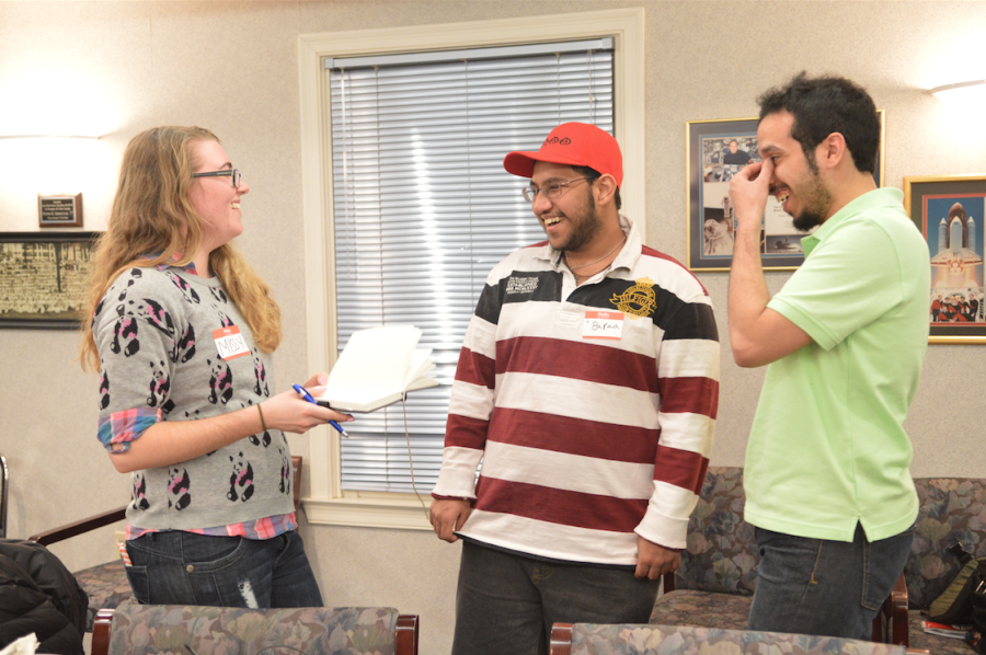 Missy Hendrix, a public health major, passes a book to students Baraa Iskandar and Abdullah Almotairi at the Kent State International Student Mentors Meeting on March 3, 2015. Members of the organization can leave a message in their language in the journal to share with the group. 