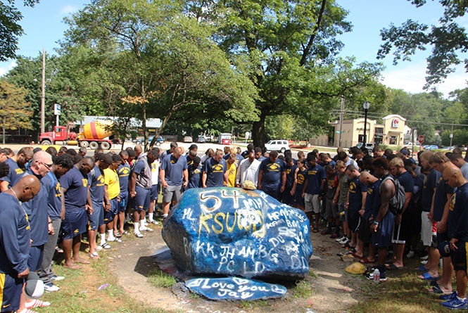 The Kent State football team prays around the rock on Aug. 20, 2015 before they paint it in honor of Jason Bitsko. Bitsko was a starting center on the football team and passed away on Aug. 20, 2014. 