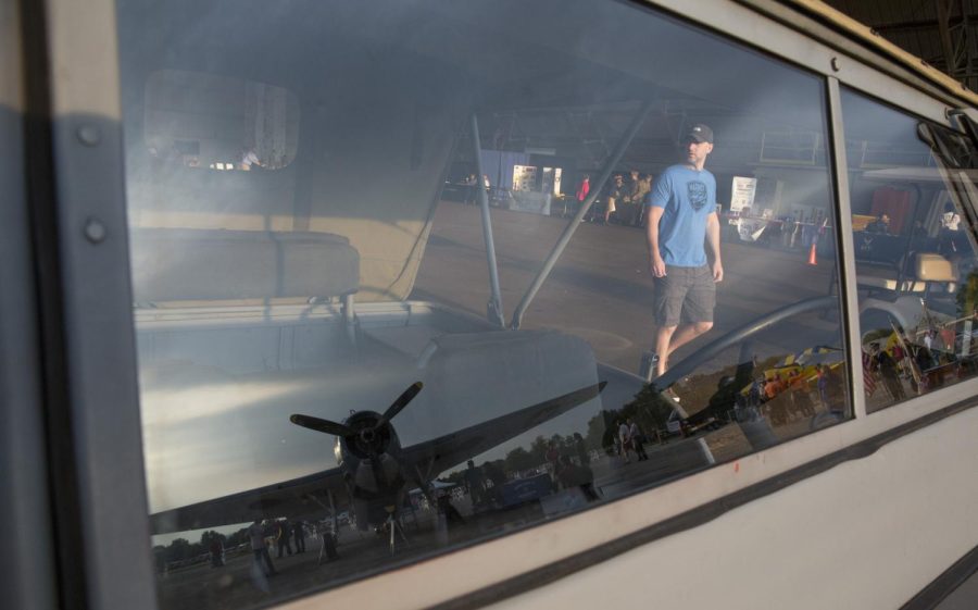 Brent Cessna, an attendee of the Aviation Heritage Festival, walks out of the hangar at the Kent State Airport. Reflected in the window of a Willis Jeep, is a World War Two U.S. Navy TBM-3E Avenger. Saturday, Sept. 19, 2015.