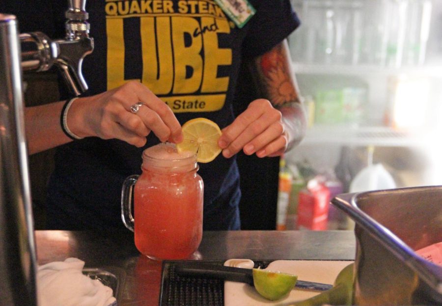 Bartender and senior public communications major Jennifer Reihner puts the final touches on a spiked pink lemonade drink at Quaker Steak and Lube in the Student Center on Monday, Oct. 5, 2015. Quaker Steak and Lube is the only official location that serves alcohol on campus.