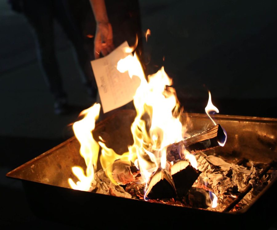 Students toss papers with names of perpetrators into a fire outside of the M.A.C. Center during Take Back the Night on Monday, Oct. 5, 2015.