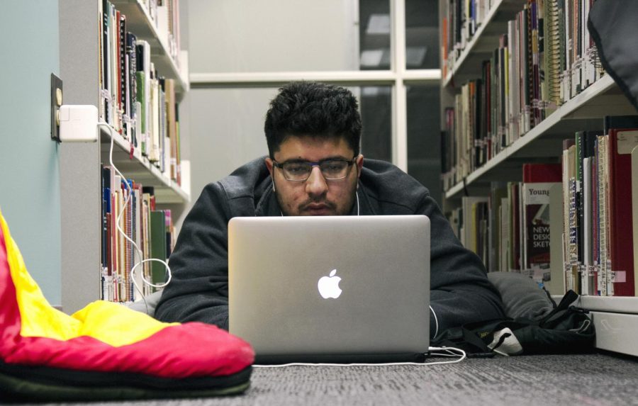 Computer engineering major, Madhur Malhotra, of the University of Pittsburgh, camps out on his sleeping bag while working on his team’s project in Rockwell Hall library on Jan. 30, 2016 as part of the Kent Hackathon.