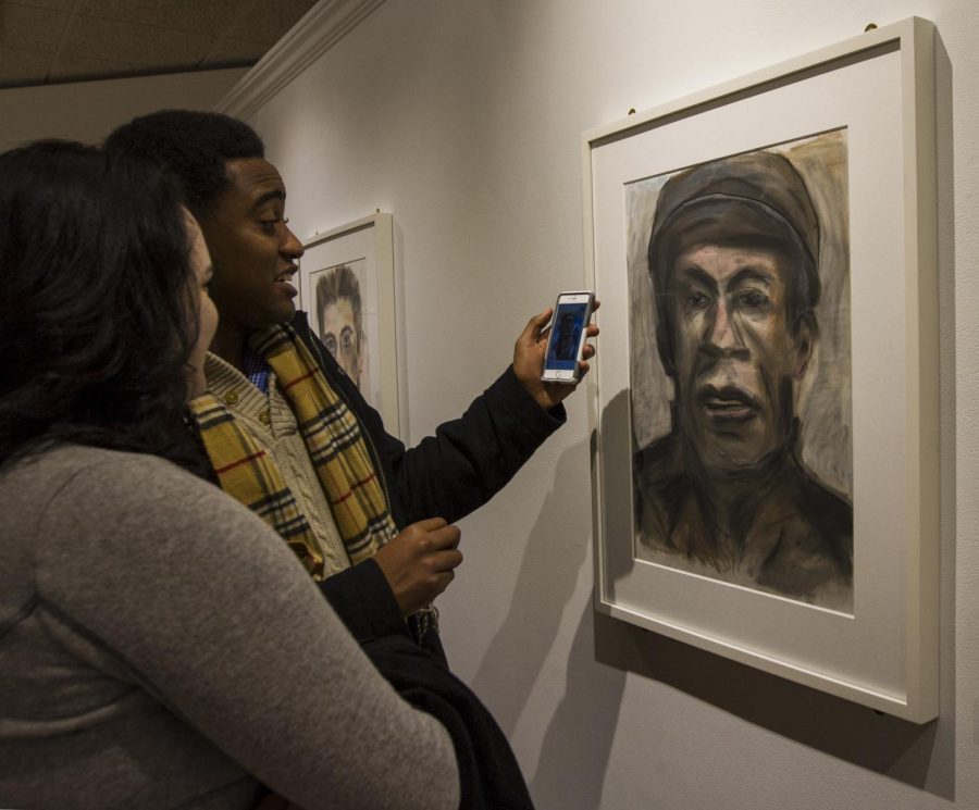 Kent State freshmen Kelly Cunningham and sophomore theatre studies major Jordan Euell ponder who they think this portrait by musician Bob Dylan might be. “I think it looks like John Henry,” Kelly said. Jordan then pulled up a drawing of Henry on his phone for comparison. The McKay Bricker Gallery on Main Street in downtown Kent is currently hosting the portrait series from Feb. 21 to Mar. 5.