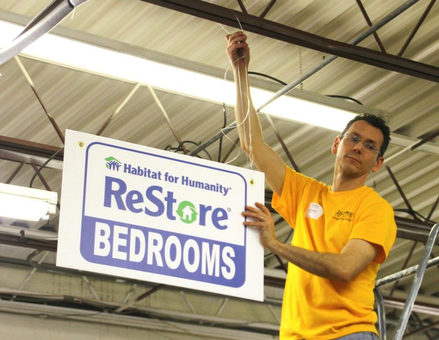 Kent State alumni Michael Bruder hanging up store signs as part of community service at the Habitat for Humanity ReStore on Saturday, April 12, 2014.