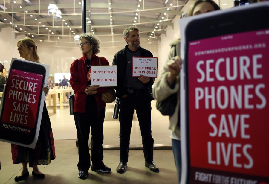 Protesters, from left, Sandra Bell, Victoria Best, and Charles Fredricks, hold signs in support of Apple store in Santa Monica, Calif., on Tuesday, Feb. 23, 2016. Rallies were planned at Apple stores across the country to support the companys refusal to help the FBI access the cell phone of a gunman who took part in the killings of 14 people at the Inland Regional Center in San Bernardino.