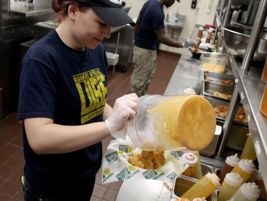 Freshman public relations and advertising major Madeline Crandall pours sauce over wings during a lunch shift on Friday, April 15.