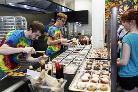 Alex Stayer (left) and Donnie Cuthbert (center) add the finishing touches to customers’ orders at Peace, Love & Little Donuts in downtown Kent on Friday, June 10, 2016.