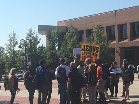 Students gather around religious protester in Risman Plaza on Oct. 6, 2016. Some students carried signs that read Free Hugs and Love Trumps Hate.