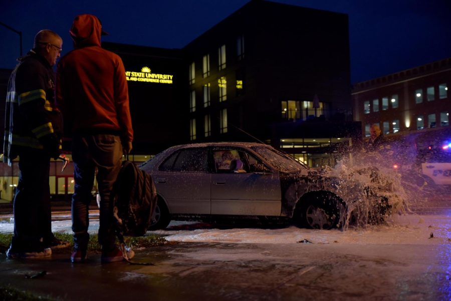 Alex Dailey, a University of Akron student, stands with his belongings and talks with a firefighter outside of the Kent State University Hotel and Conference Center after his car was involved in a one-car fire Tuesday, Nov. 8, 2016. Dailey was driving through Kent when his car began to smoke and he noticed liquid leaking from his car, before the hood of his car ignited in flames.