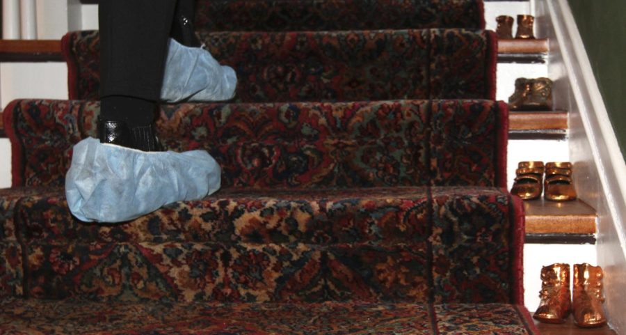 A community member wearing shoe covers walks up the stairs of a house built in 1887 owned by Alice Christie, who received her Ph.D. from Kent State in 1992, during the 15th annual Sugar Plum Tour in Akron, Ohio, on Sunday, Dec. 4, 2016.