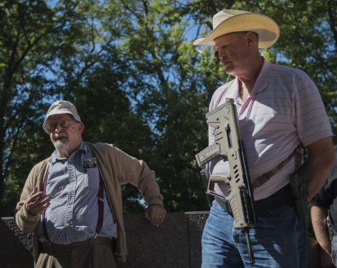 Professor Jerry Lewis, left, talks about his first hand experiences at the May 4th shooting to a group of open carry gun walkers like Jeffry Smith, right, at the May 4th memorial Saturday Sept. 24, 2016.