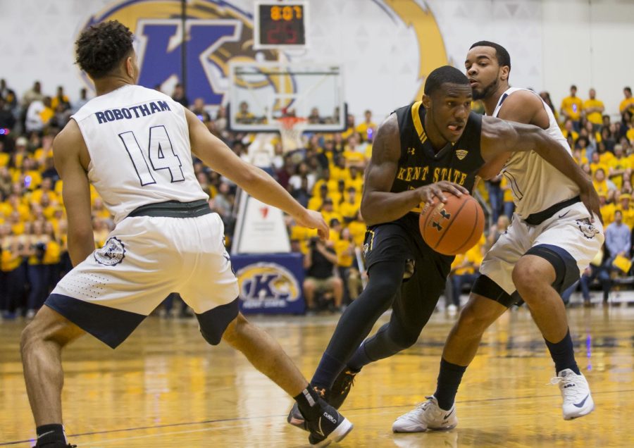 Kent State senior guard Deon Edwin splits through Akron junior guard Noah Robotham and sophomore guard Josh Williams at the M.A.C. Center on Friday, March 3, 2017. Kent State lost 66-56.