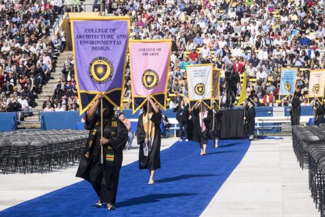 Selected students carry gonfalons representative of Kent States colleges down the blue carpet toward the stage to start off commencement at Dix Stadium on Saturday, May 13, 2017.