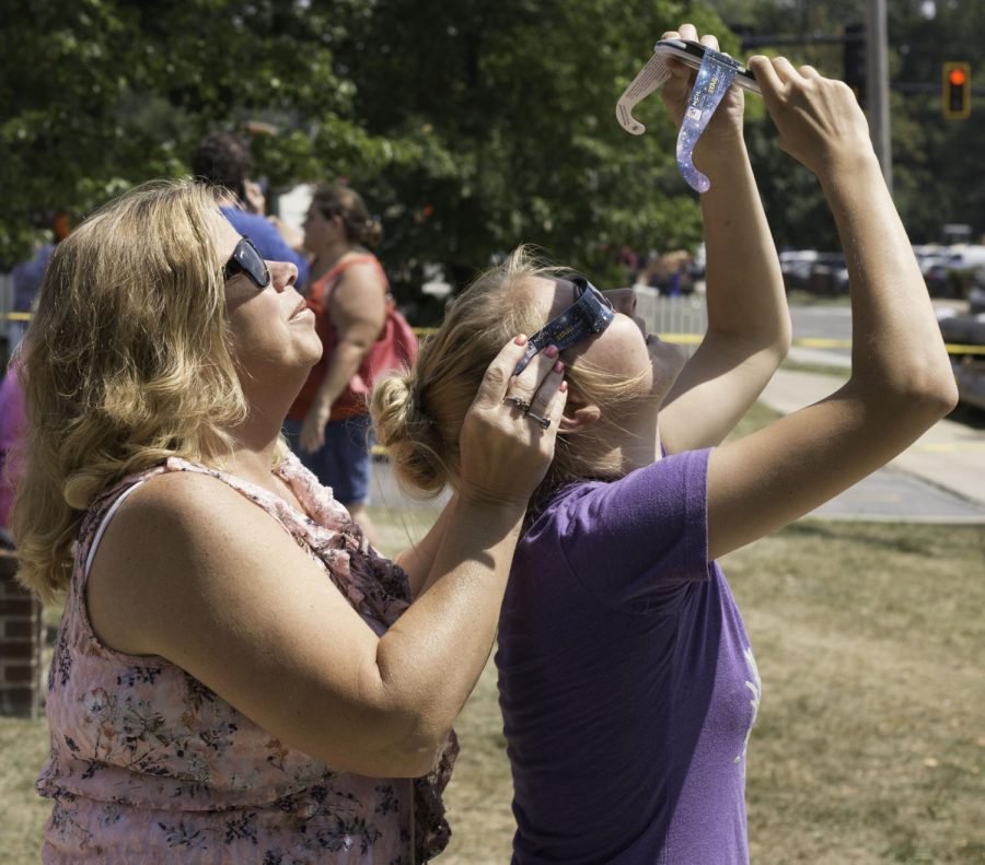 Christie Stickle, 45, of Ravenna, Ohio, holds eclipse glasses over Jenna Summy, a freshman scenic design major, as she takes a photo with her smartphone of the eclipse on Monday, Aug. 21, 2017