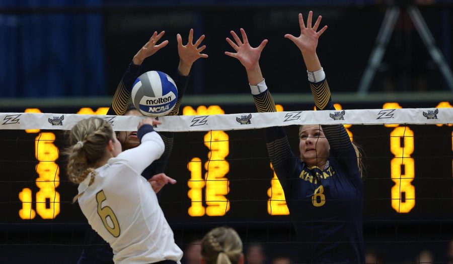 Kent State opposite Heather Younkin (left) and middle blocker Annie Ennesser block a spike during a match against Akron Friday, Sept. 22, 2017.