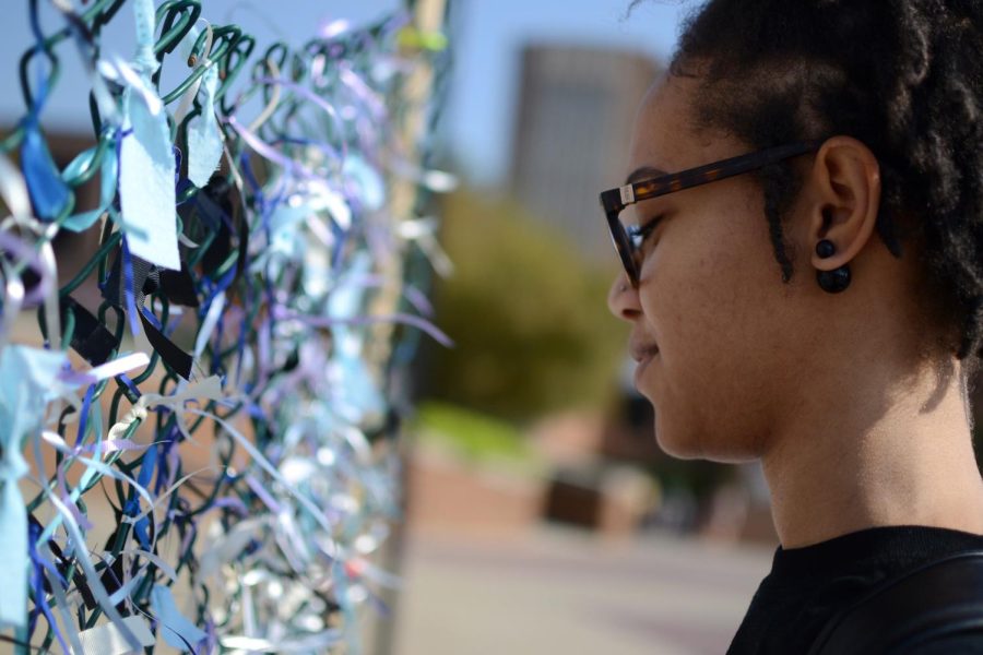 Sameera Bowles, a senior Pan-African studies major, tied a ribbon on the fence. SASA set up the fence to raise awareness for those affected by sexual assault.