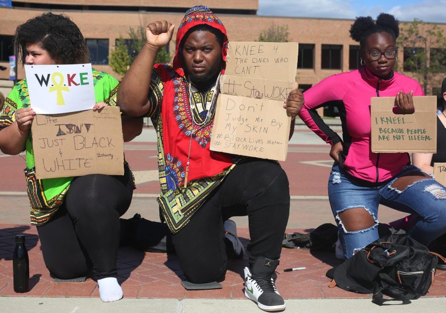 Suleika Carlo-Ramos (left), a sophomore biology major, Richard Gibson and Taniyahh Lennon, both sophomore psychology majors, participate in the Take a Knee demonstration in Risman Plaza Thursday, Sept. 28, 2017. 