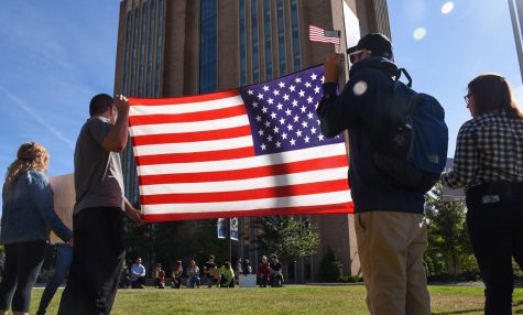 Kevin Wynne, a senior geography major (right) and Harrison Sorm, a freshman psychology major, hold the American flag with their organization Turning Point USA in front of counter-protesters on Risman Plaza on Monday, Oct. 2, 2017.