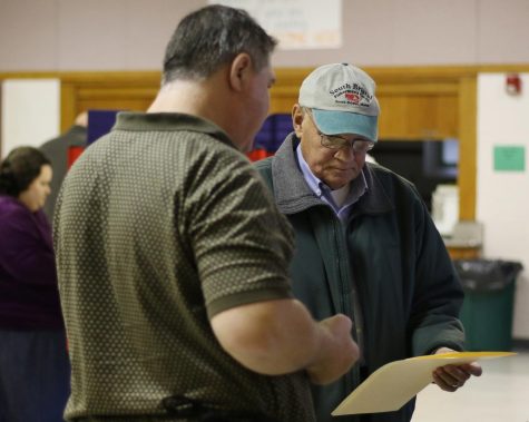 Ralph Kletzien (right) of Kent, Ohio, turns in his ballot and receives an “I voted” sticker at the Kent United Church of Christ polling station Tuesday, Nov. 7, 2017.