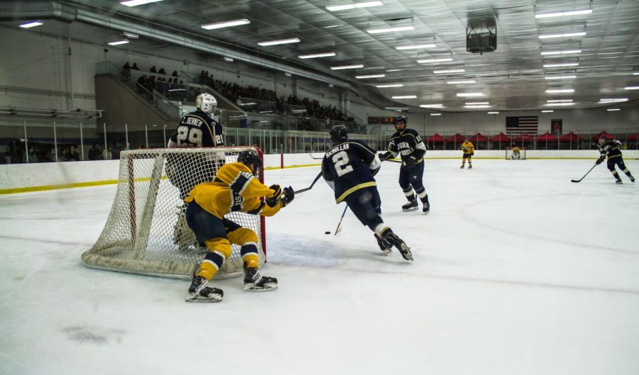 A+Kent+State+defender+reaches+out+for+the+puck+as+John+Carroll+senior+defenseman+Grant+MacMullen+skates+past.%C2%A0