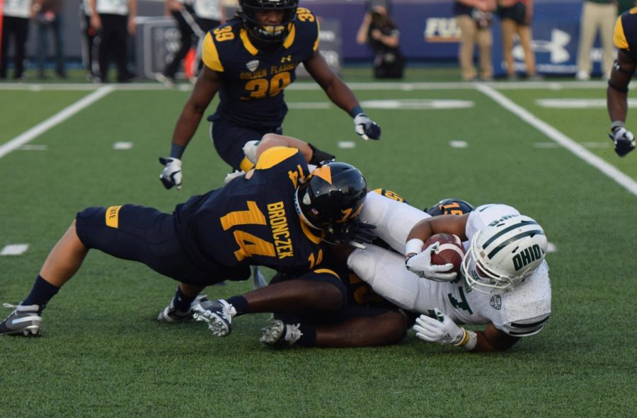 Kent State’s John Henry Bronczek (14) and Keith Sherald Jr. (15) tackle an Ohio ball-carrier on during their matchup against the Bobcats on Oct. 6, 2018. Kent lost the game, 27-26.