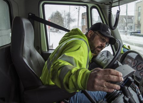 Jeff Derthick, a snow plow operator, checks his side-view mirrors as he prepares to drive through an intersection on Chestnut Street in Ravenna Saturday. 