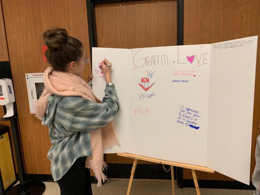 Andrea Specht, a senior special education major, draws on the graffiti of love poster.