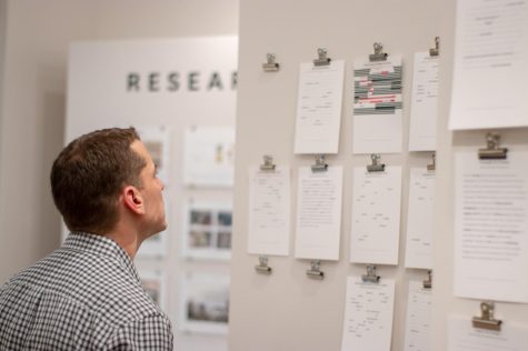 Grant Fletcher, an adjunct visual communication design professor, looks at Emerge poems created by visitors of the Traveling Stanzas exhibit in Taylor Hall on Wednesday, Feb. 7, 2019.