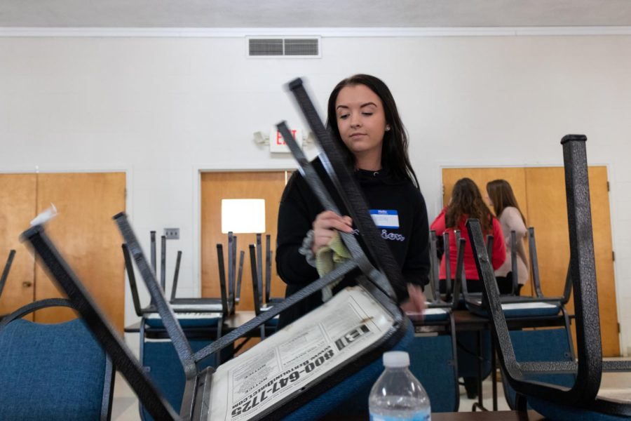 Kent State volunteer Lindsay Kaminski stacks chairs after Loaves and Fishes lunch Feb. 9.