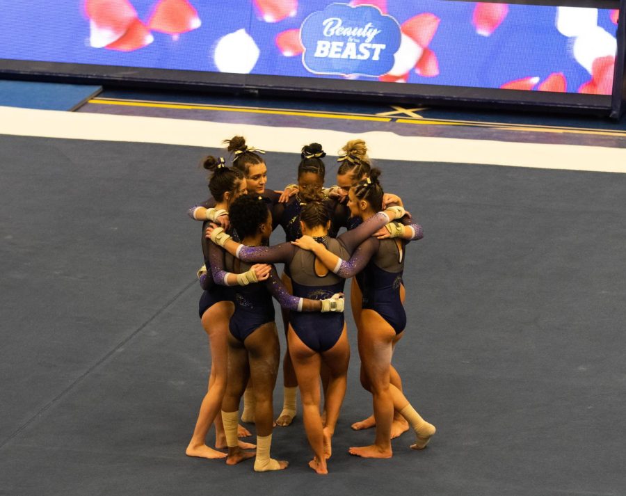 The Gymnastic team meets in the center of the mat before the Floor Routines started at the Beauty and the Beast match on February 10, 2019.