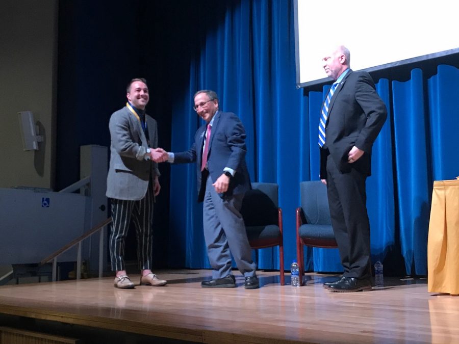 Evan Neal (left), a senior fashion design major, shakes hands with Paul DiCorletto (right), vice president for research after receiving his award for first place in the fashion design category at the Undergraduate Research Symposium on April 9. 