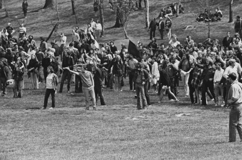Protesters crowd the edge of the Commons below Taylor Hall as they shout and gesture at National Guardsmen during the disturbances on the Kent State campus May 4, 1970. At left, in a cowboy-style shirt and wearing a headband, is Jeffrey Miller, who was killed later that day. 
