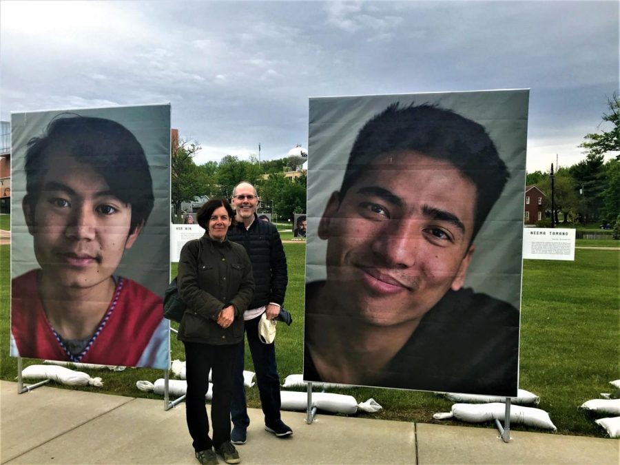 Françoise Massardier-Kenney (left) and Paul Haridakis (right) stand in front of two photos of refugees from Northeast Ohio on Tuesday, May 21, 2019. The two Kent State professors lead the Global Understanding Research Initiative that organized the exhibit.