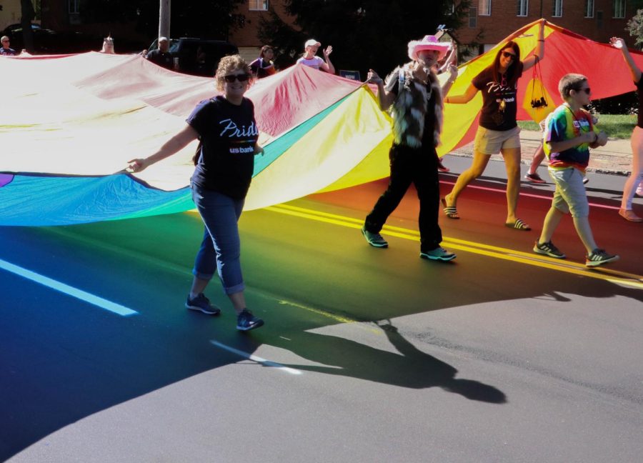 A group of people walking in the parade carry a giant LGBTQ+ flag down the middle of the street in a pride parade in Akron, Ohio on Aug. 24, 2019.