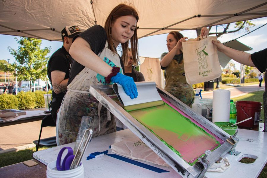 Jenna Miley prints a design on a cotton bag at the United Print Alliance booth during the Kent Creativity Festival on the Lester A. Lefton Esplanade. Sept. 28, 2019.