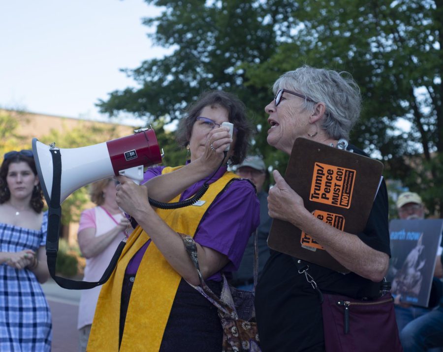 Reverend Renne Zimelis-Ruchotzke holds the microphone for Cheryl Lessin as she tells the crowd about a non-violent protest in Washington D.C. that will push against what she called the 