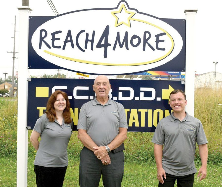 Shirley Bowald, Paul Anthony, and Michael Reiner in front of the Reach 4 More sign. 