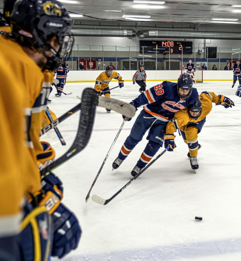 Junior forward Rubin Chavarria chases after the puck while Syracuse forward William Franzese pushes against him during Kent State's game against Syracuse on Saturday, Oct. 5, 2019.