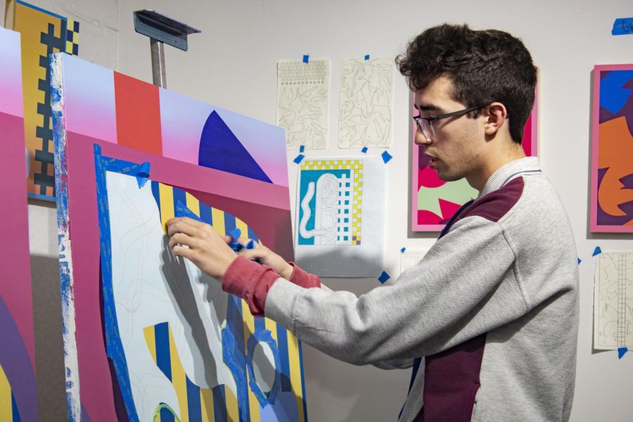 Griffin Allman, senior painting and art education double major, peels tape away from one of his canvases. Allman likes to use more abstract designs that way people can interpret it in their own personal ways.