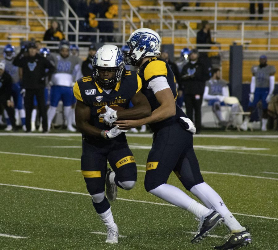 Quarterback Dustin Crum (14) hands the ball off to Xavier Williams (18), during the football game on Nov. 14, 2019. The Flashes beat the University of Buffalo 30-27.