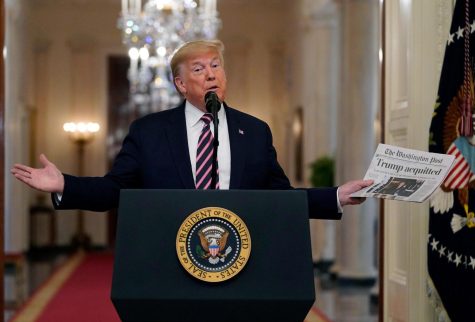 President Donald Trump holds up a newspaper with a headline that reads Trump acquitted as he speaks in the East Room of the White House, Thursday, Feb. 6, 2020, in Washington. (AP Photo/Evan Vucci)