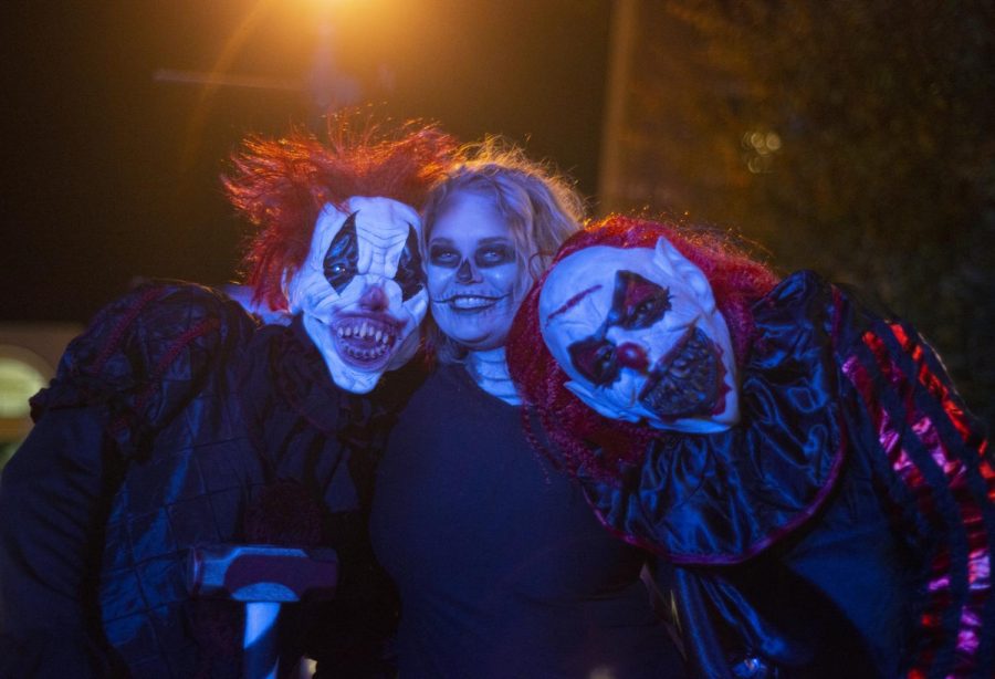 Kaitlyn Goldinger takes a photo with 2 clowns downtown during Kent Halloween early Oct. 27, 2019.