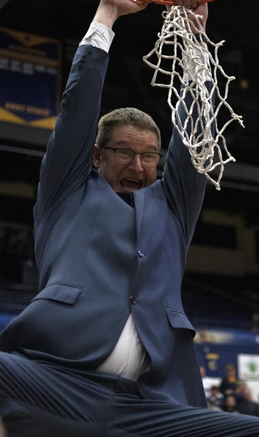 Head coach Todd Starkey swings from the net after he cuts it down on Mar. 4, 2020 to celebrate Kent State Women's basketball becoming the MAC East champions. Kent State University women's basketball beat Ohio University 81-77.