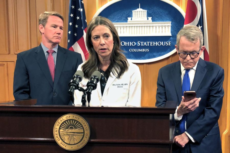 Dr. Amy Acton, Ohio Department of Health Director, center, discusses the confirmation of Ohios first three cases of coronavirus, as Gov. Mike DeWine, right, studies an update on the cases provided to him during a news conference, Monday, March 9, 2020, in Columbus, Ohio. Lt. Gov. Jon Husted is at left. Acton said the state is leaning in and taking an aggressive approach to combating the disease. (AP Photo/Andrew Welsh-Huggins)