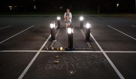 Avalyn Lund-Goldstein stands vigil inside the memorial space where Sandra Scheuer was shot in the Prentice Hall parking lot by Ohio National Guardsmen at Kent State University on May 4, 1970. The coronavirus forced the university to move the 50th anniversary commemoration events to virtual formats, but a small group of marchers still walked across campus as they have for 50 years since the shooting. Following the march, four people held candles in the spaces where each student fell.