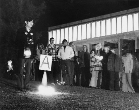 A man stands near a cone marked with an A and holds a lantern on May 3, 1971, while others look on during the first candlelight vigil commemorating the shootings at Kent State on May 4, 1970.