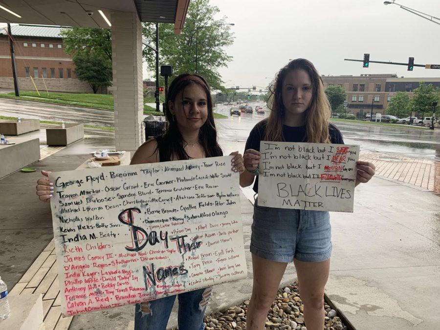 Kent Roosevelt High School sophomores Claire Lovinski (left) and Helen Plicka (right) hold up their water-logged signs in front of the Kent Police Department building on the corner of North Water Street and West Main Street.