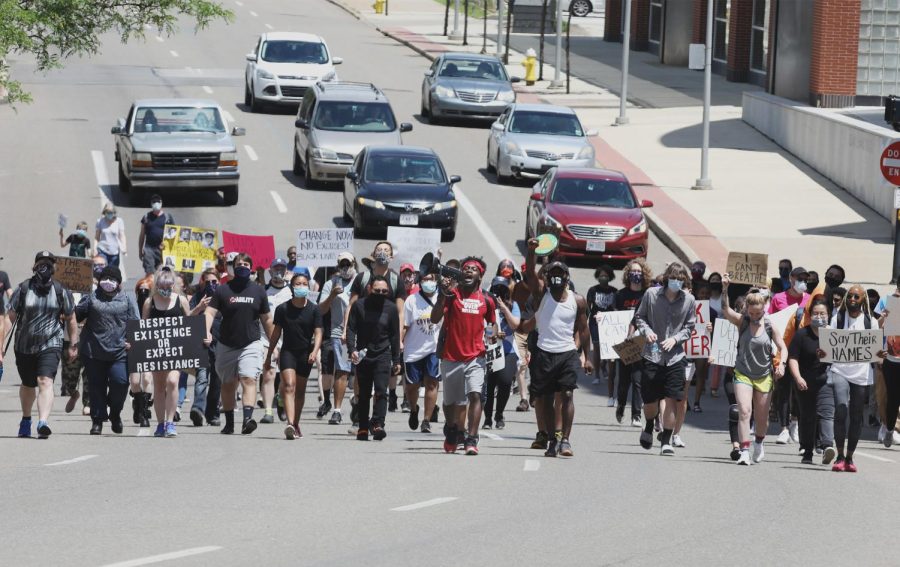 Davontae Winchester, wearing a red shirt, shouts into a megaphone as he leads about 100 marchers south on S. High St. in Akron toward the Harold K. Stubbs Justice Center June 7, 2020. The group looped out of downtown through the University of Akron campus to the east side, then made their way back downtown.