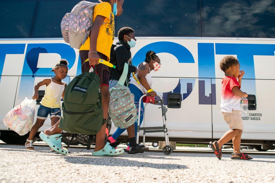 A family walks to a charter bus that will evacuate them from Galveston Island to Austin in anticipation of impact from Hurricane Laura on August 25, 2020, at the Galveston Housing Authority offices in Galveston.