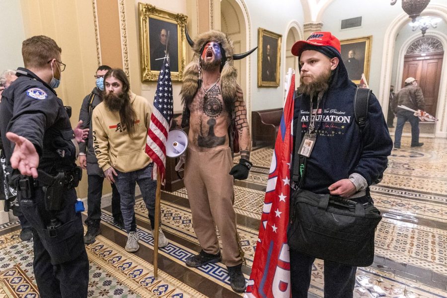 Supporters of President Donald Trump, including a man identified by CNN as Jake Angeli (center with horns), known as the QAnon Shaman, are confronted by Capitol Police officers outside the Senate Chamber inside the Capitol, Wednesday, Jan. 6, 2021 in Washington. (AP Photo/Manuel Balce Ceneta)